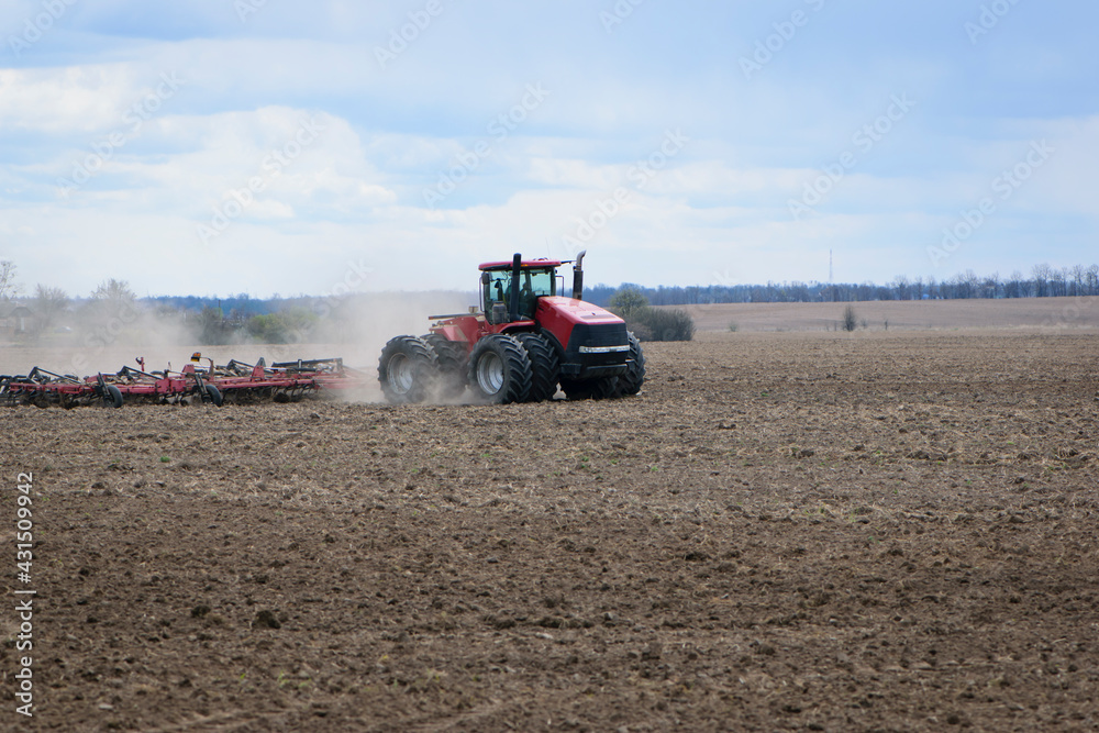 Obraz premium Red tractor with a plow on an agricultural field. work in the field with a big tractor. modern red tractor in the agricultural field. mechanism, Tractor plowing land. Harvester sowing wheat.