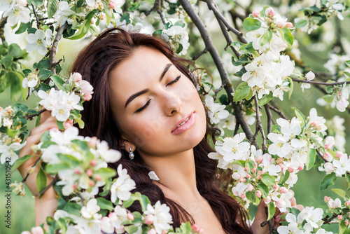close-up portrait of a beautiful woman in a spring garden. A girl with her eyes closed inhales the fragrance of flowering trees.