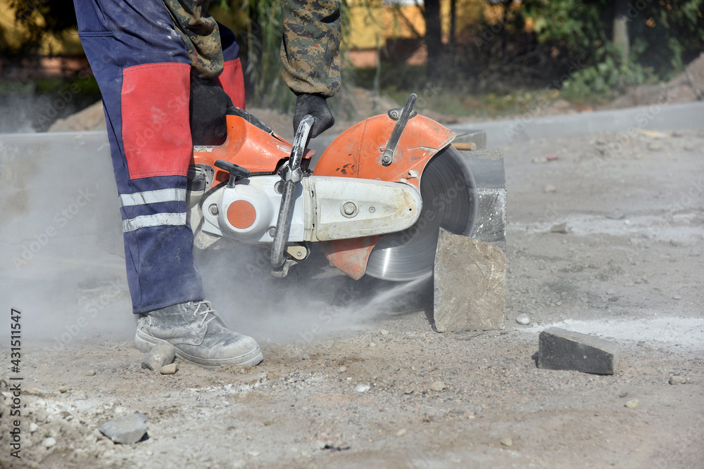 Construction site, a worker sawing a concrete block with a circular saw.