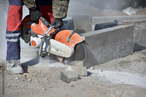 A worker saws a concrete block with a circular saw, a lot of dust.