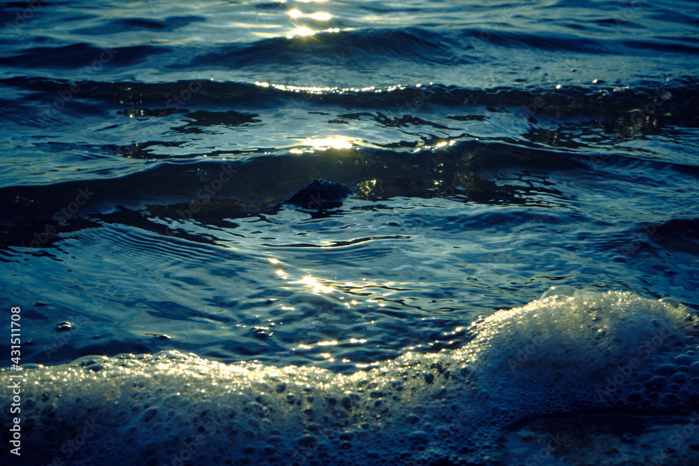 Waves and foam on the beach during sunset.