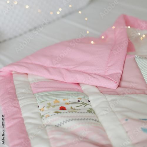 Cozy baby cot with pink patchwork blanket. Baby bedding. Bedding and textile for nursery. Nap and sleep time © paralisart