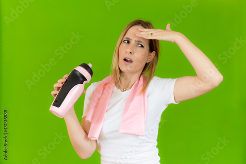 Image of a beautiful happy cheerful young sports woman posing tired isolated indoors drinking water with towel on neck.