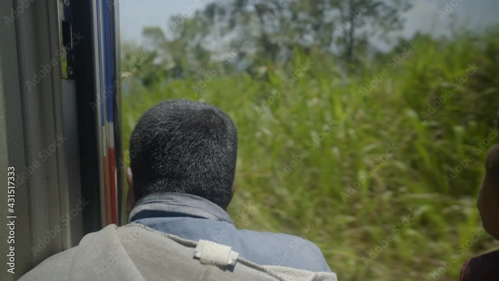 Man in the train door opening watching the view of Sri Lanka Man in the train door opening watching the view of Sri Lanka