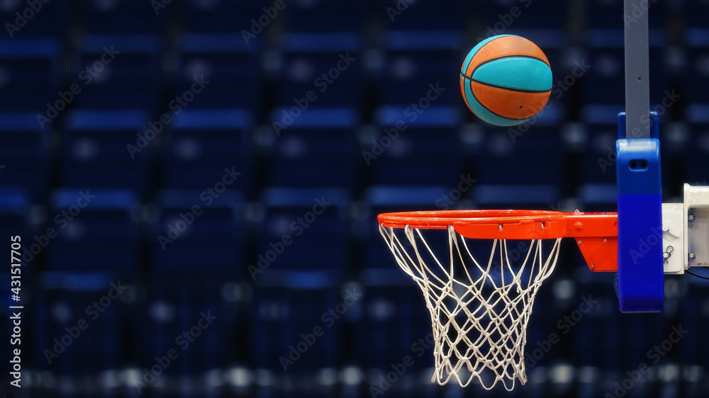 Basketball hoop with a ball on the background of the empty seats of the sports arena