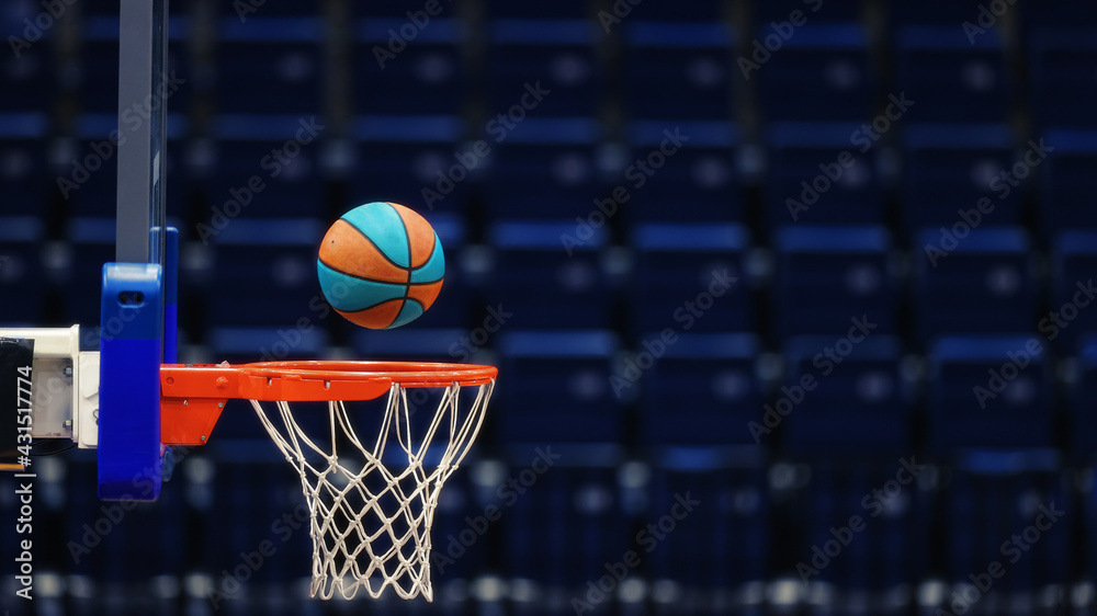 Basketball hoop with a ball on the background of the empty seats of the sports arena