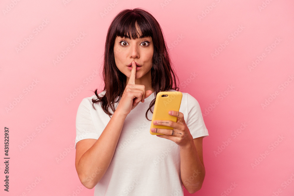 Young caucasian woman holding a mobile phone isolated on pink background keeping a secret or asking for silence. Young caucasian woman holding a mobile phone isolated on pink background keeping a secret or asking for silence.