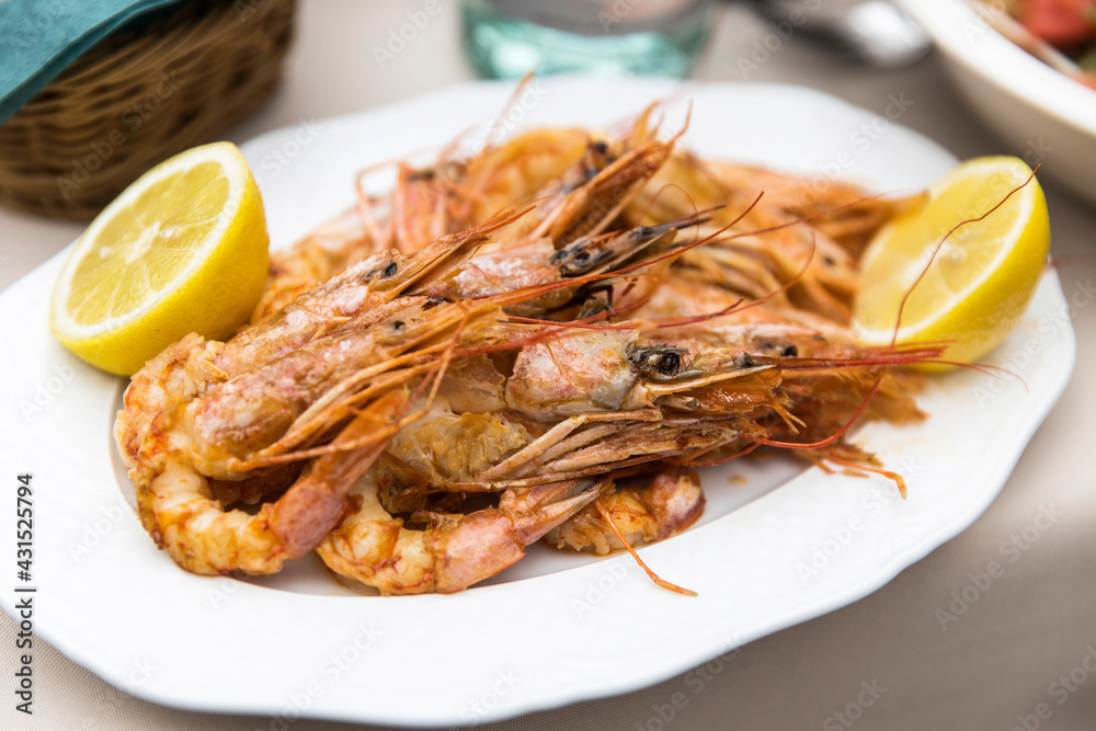Baked prawns with lemon halves on a white plate. Baked prawns with lemon halves on a white plate.