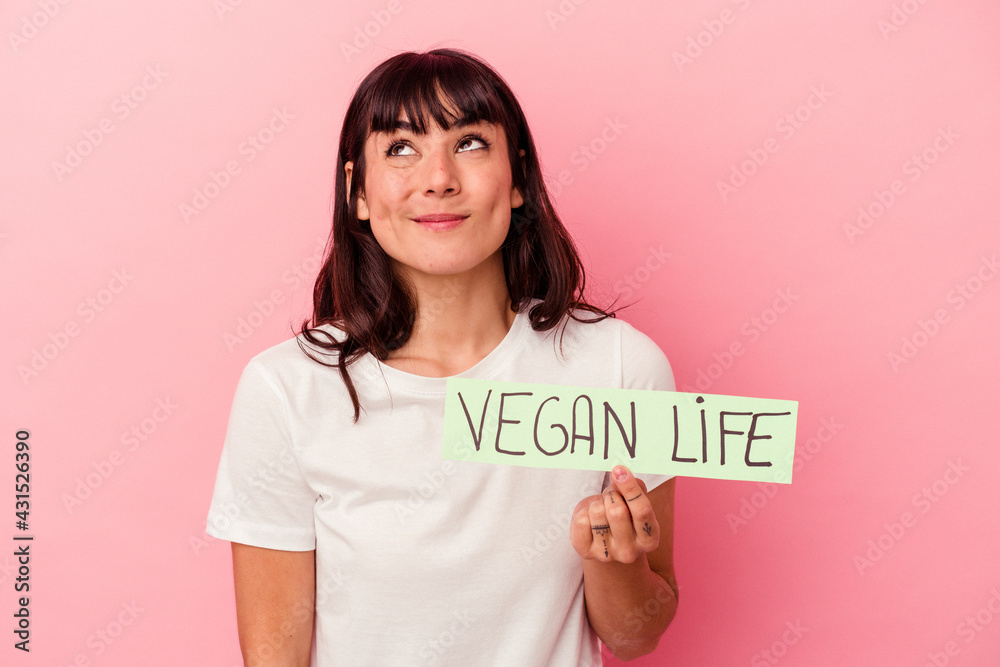 Young caucasian woman holding a vegan life placard isolated on pink background dreaming of achieving goals and purposes Young caucasian woman holding a vegan life placard isolated on pink background dreaming of achieving goals and purposes