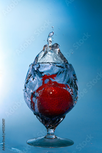 Strawberry fell with splashes in glass with liquid