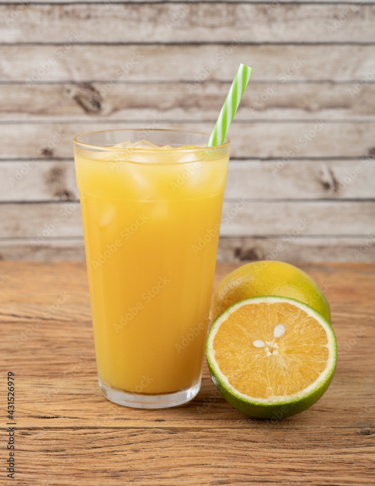 Orange juice in a glass with ice and fruits over wooden table Orange juice in a glass with ice and fruits over wooden table