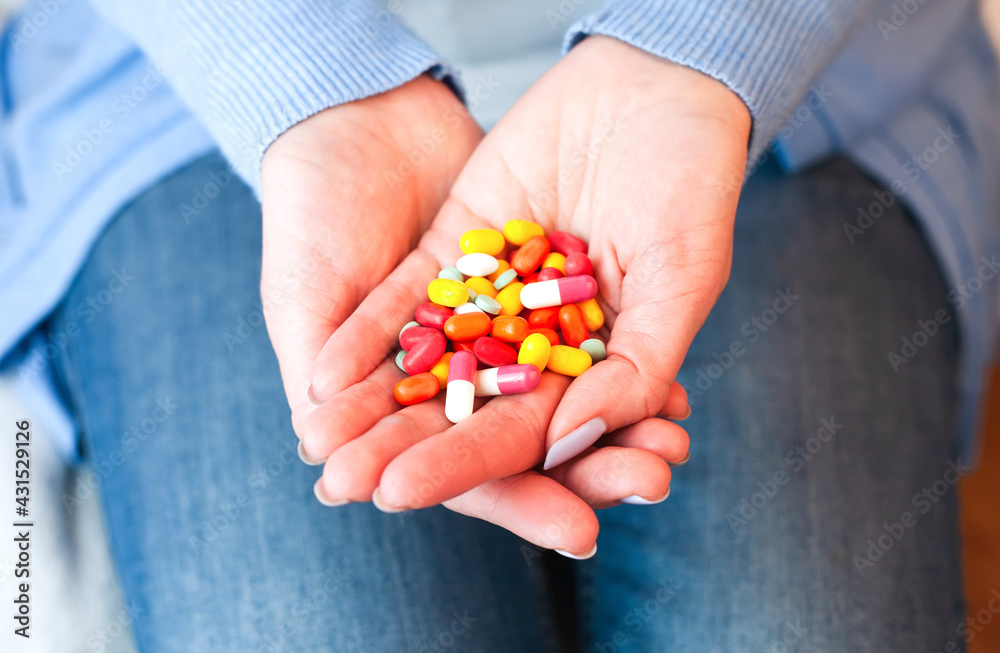 Female hands holds many multicolored pills. Taking vitamins, supplements, antibiotic, antidepressant and painkiller medication. Close-up. Female hands holds many multicolored pills. Taking vitamins, supplements, antibiotic, antidepressant and painkiller medication. Close-up.