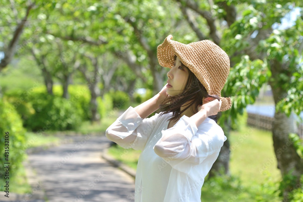 新緑の公園でポーズをとる麦わら帽子を被った若い笑顔の女性 Stock Photo Adobe Stock
