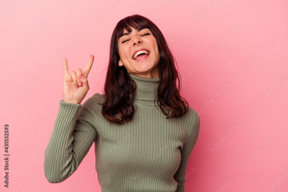 Young caucasian woman isolated on pink background showing a horns gesture as a revolution concept. Young caucasian woman isolated on pink background showing a horns gesture as a revolution concept.