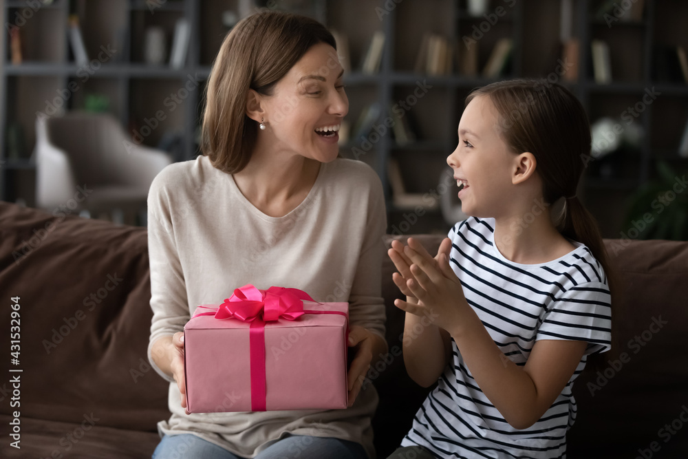 Cute little teen girl child present beautiful handmade wrapped gift to excited young Caucasian mother for Mothers Day. Happy small teenage daughter congratulate greet mom with birthday make surprise. Cute little teen girl child present beautiful handmade wrapped gift to excited young Caucasian mother for Mothers Day. Happy small teenage daughter congratulate greet mom with birthday make surprise.