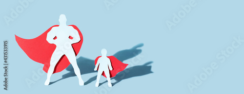 Paper cut father and child figure wearing super hero cloaks on blue background with shadows, fathers day concept, banner.