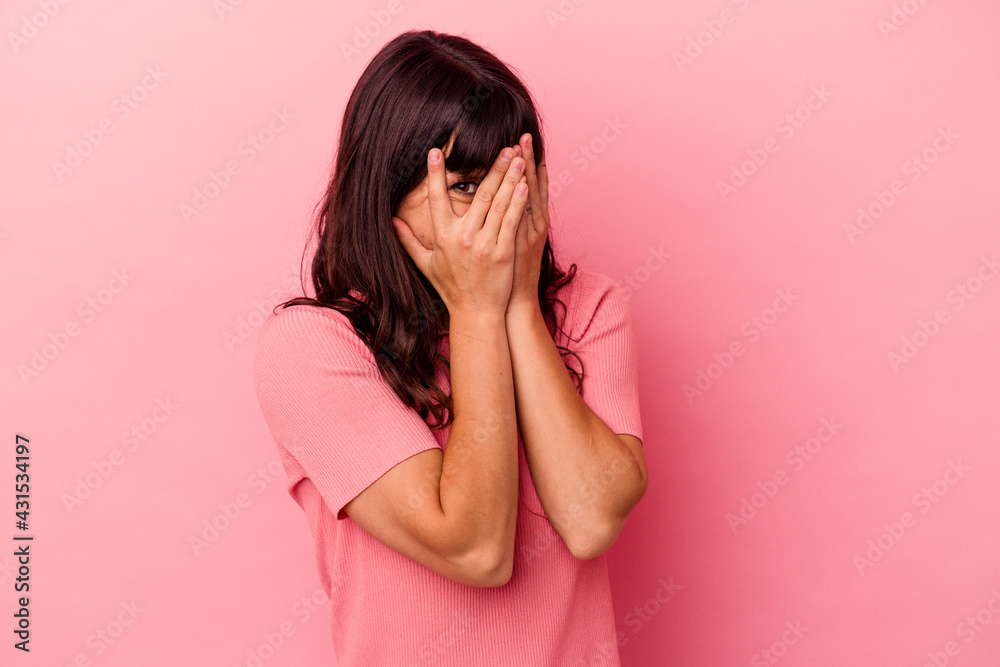 Young caucasian woman isolated on pink background blink through fingers frightened and nervous. Young caucasian woman isolated on pink background blink through fingers frightened and nervous.