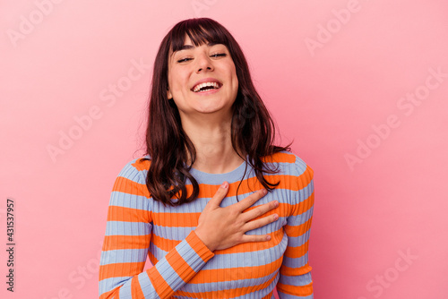 Young caucasian woman isolated on pink background laughs out loudly keeping hand on chest. © Asier