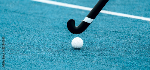 Field hockey stick and ball on blue grass. Professional sport concept