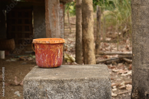 A coloring bucket is kept on a cement wall with blurred background © Bijaya Kumar