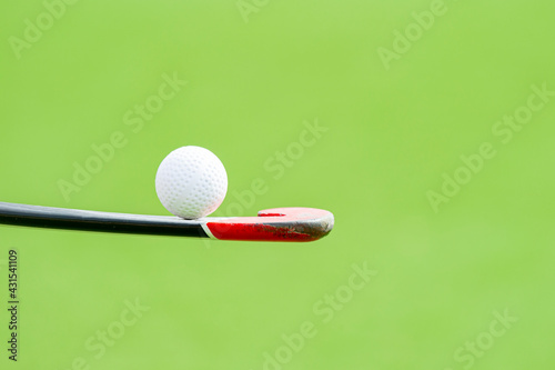 Field hockey stick and ball on green background. Professional sport concept photo