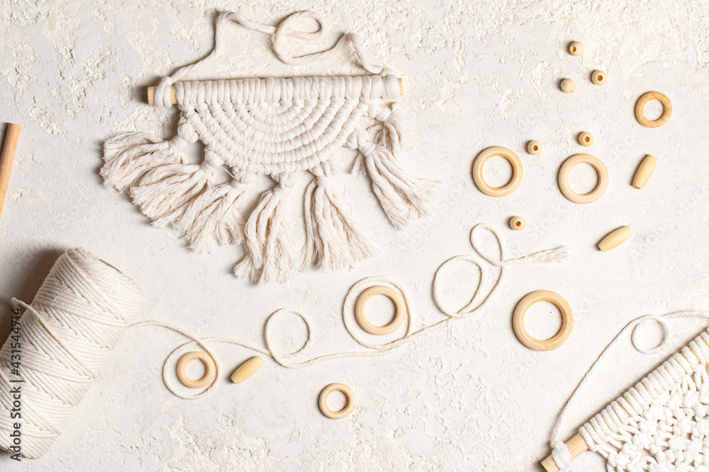 Macrame accessories on cream color background. Creative hobby concept. Top view