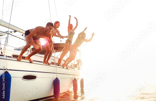 Photography Side view of young crazy friends jumping from sailboat on sea ocean trip - Men a