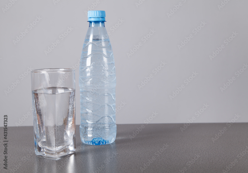 Water bottle and glass, on gray background. Water bottle and glass, on gray background.