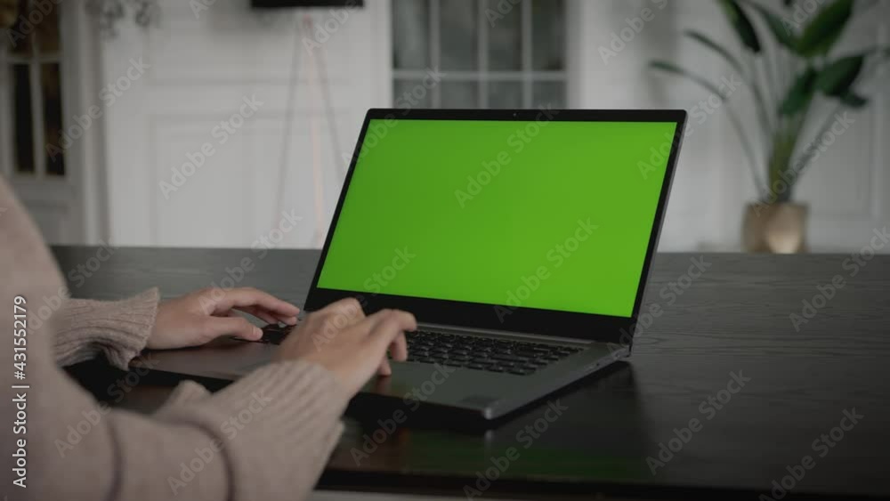 Woman is working with laptop, searching the web. Laptop green display with copy space mockup. Woman hands and keyboard on black table in living room interior Woman is working with laptop, searching the web. Laptop green display with copy space mockup. Woman hands and keyboard on black table in living room interior