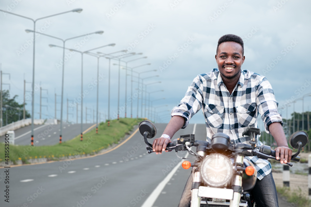 African biker man riding a motorcycle rides on highway road