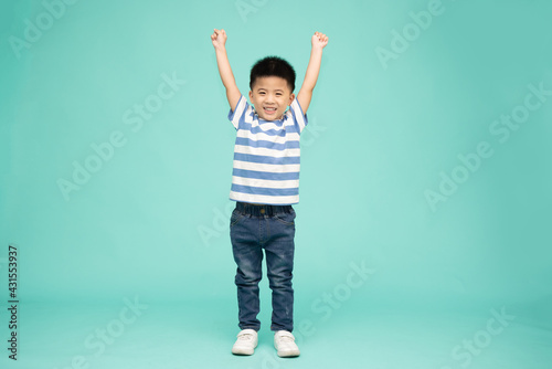 Cute Asian boy showing winner sign with his hands up isolated on green background