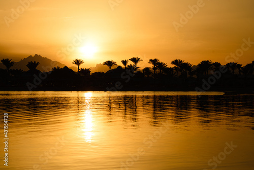 Sunset on the sea with mountain view and palm trees
