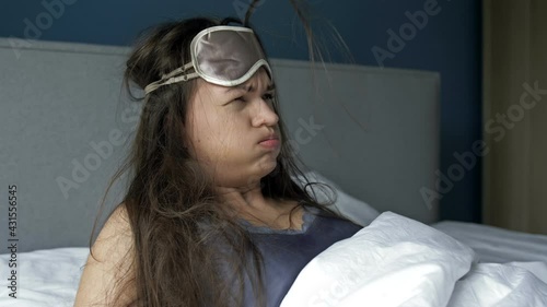 Young woman waking up suffering headache and hangover after drinking alcohol.