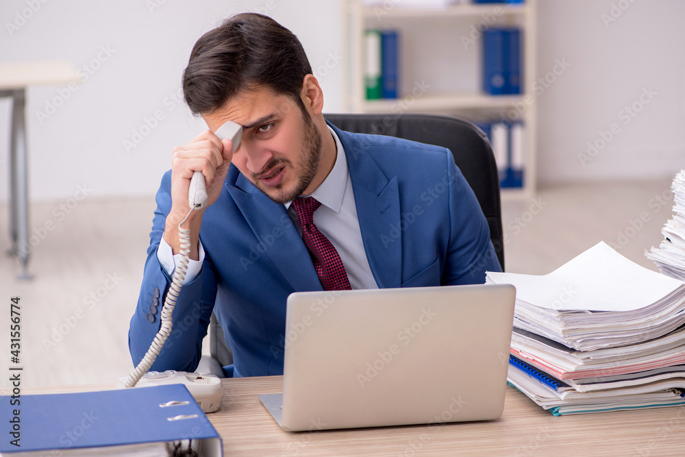 Young male employee and too much work in the office