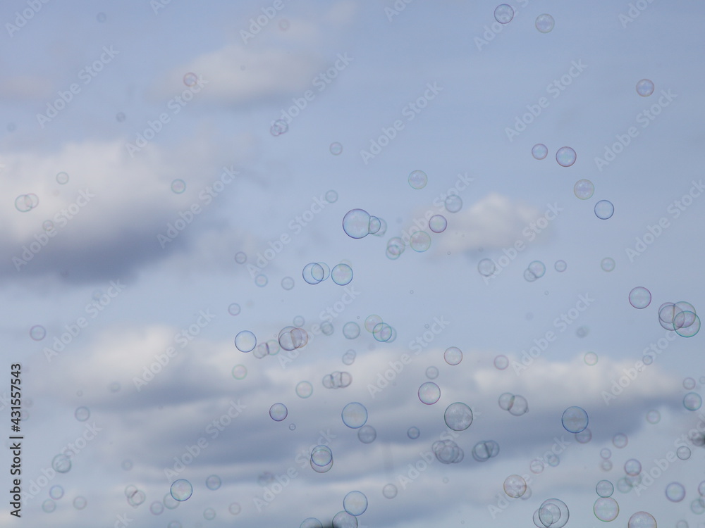 Little soap bubbles against a blue sky with white clouds texture for background