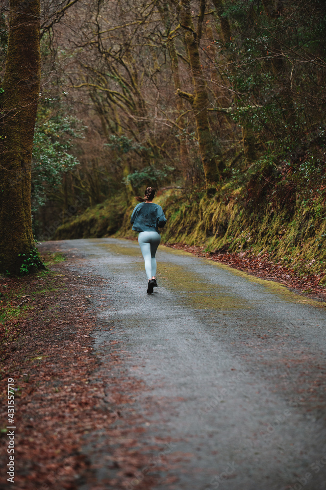 Unrecognizable woman jogging on rural road in autumn park Unrecognizable woman jogging on rural road in autumn park