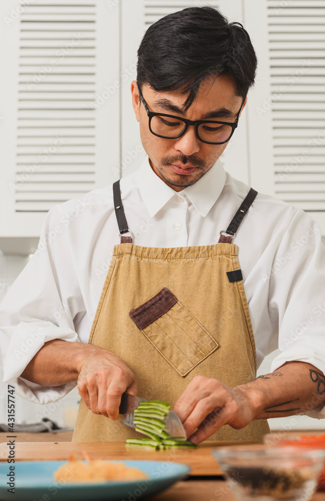 Sushi master chef slice fresh cucumber on chopping board in the kitchen. Knife in motion Sushi master chef slice fresh cucumber on chopping board in the kitchen. Knife in motion