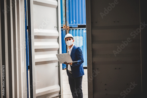 Businessman, executives and engineers wear medical face masks and helmet, While inspecting industrial plants and warehouses for international shipping businesses Concepts of import and export