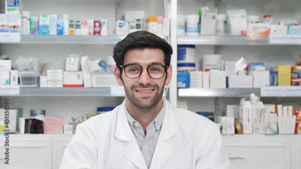 Middle eastern male pharmacist smiling confident and looking at the camera in modern pharmacy. Slow motion Middle eastern male pharmacist smiling confident and looking at the camera in modern pharmacy. Slow motion