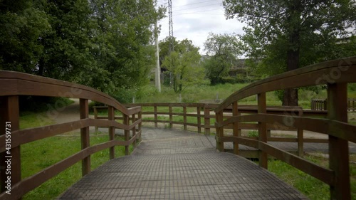 brown wooden bridge in the middle of nature on a path to cross a river. rural structure for ecological trail. country road with decorative wooden walkways.