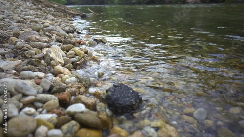 river bank with colored stones and crystal clear water with unfocused background. shore of the river tea de puenteareas.