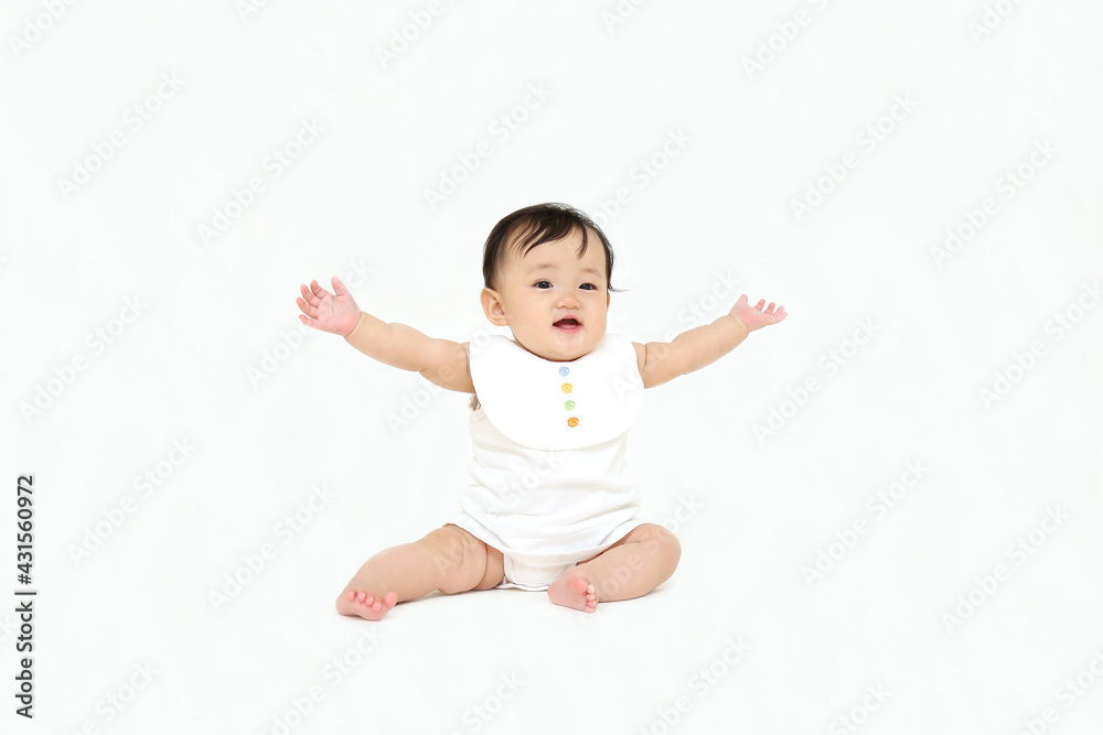 白背景でお座りする女の子の赤ちゃん。成長,健康,元気,育児イメージ