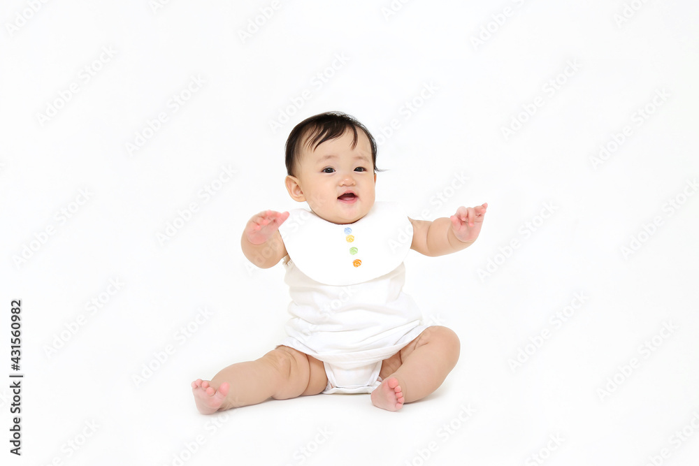 白背景でお座りする女の子の赤ちゃん。成長,健康,元気,育児イメージ