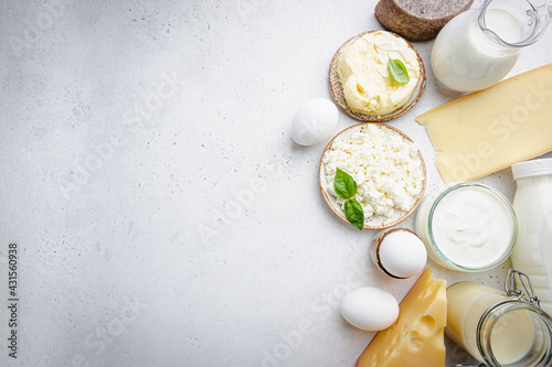 Fresh dairy products, milk, cottage cheese, eggs, yogurt, sour cream and butter on white table, top view