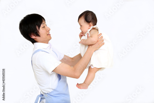 エプロン姿の若いお父さんが赤ちゃんを抱き育児をするイメージ