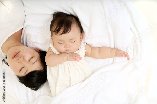 新生児と一緒に昼寝するお母さん。育児疲れイメージ