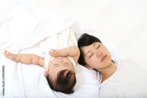 新生児と一緒に昼寝するお母さん。育児疲れイメージ