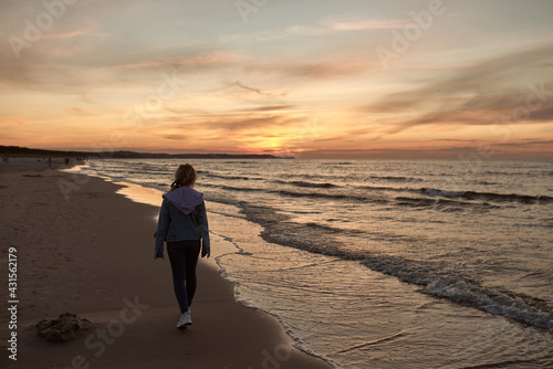beautiful natural girl walking and admiring the sunset by the sea,