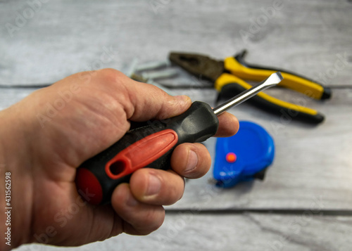 A black locksmith screwdriver in his hand on a gray background.