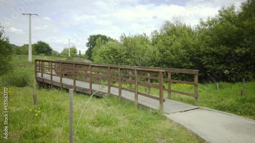 brown wooden bridge in the middle of nature on a path to cross a river. rural structure for ecological trail. country road with decorative wooden walkways.
